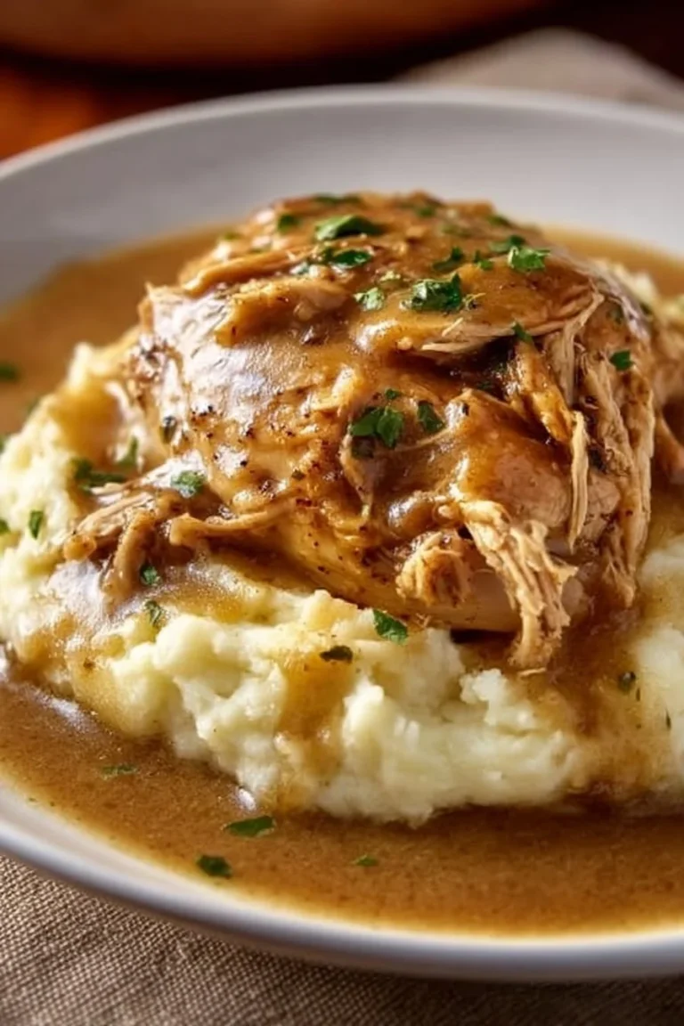 Crockpot chicken and gravy served on a plate with mashed potatoes