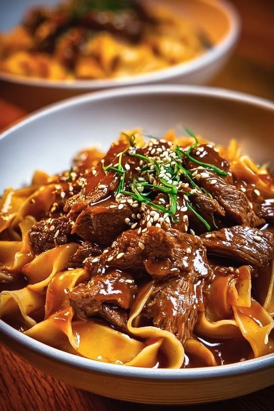 Delicious Korean beef noodles garnished with fresh vegetables and herbs.
