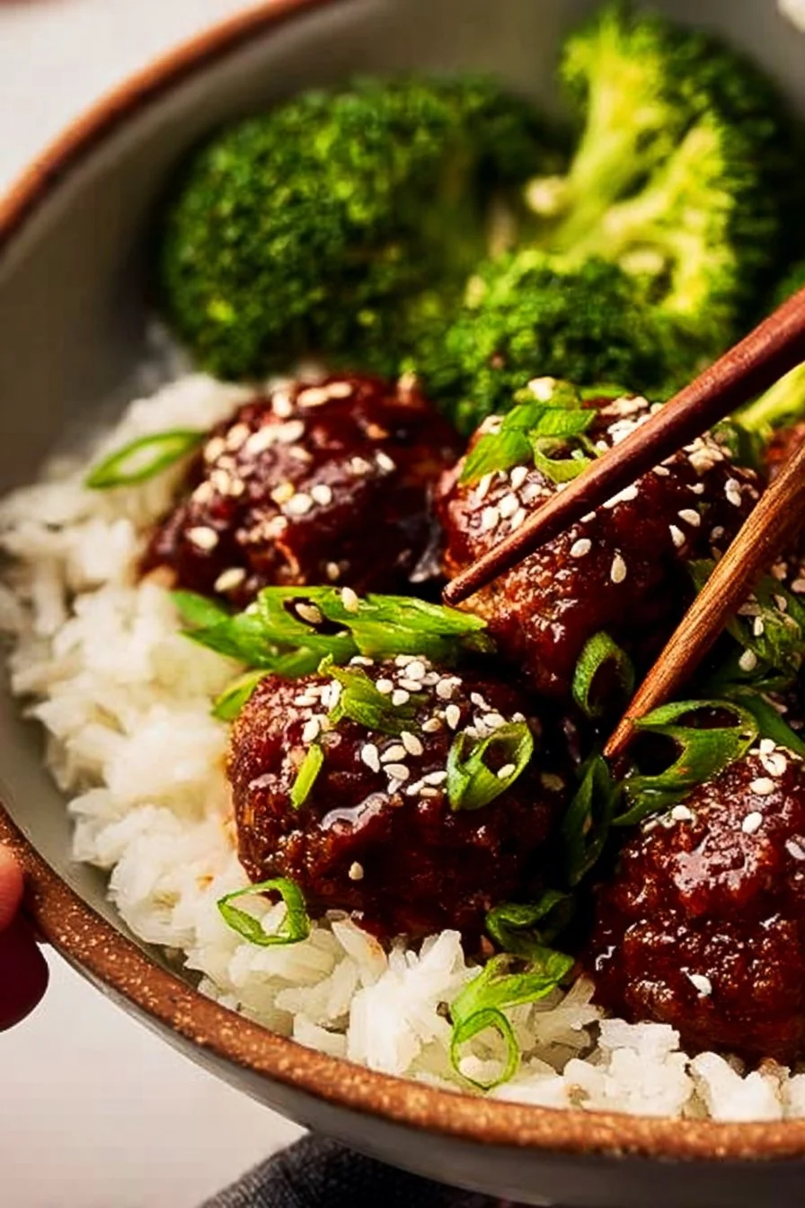 Delicious sticky Mongolian beef meatballs on a plate, garnished with green onions.